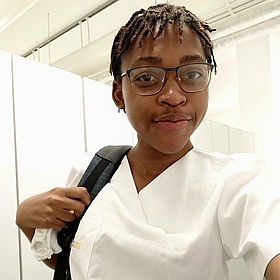 Joven estudiante sonríe con su ropa de trabajo blanca como enfermera 