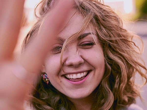 Mujer joven con cabello rubio rizado sonriendo a la cámara