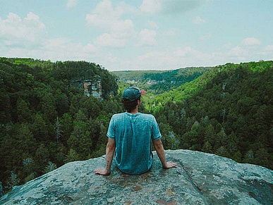 Joven se sienta en una roca y mira la naturaleza