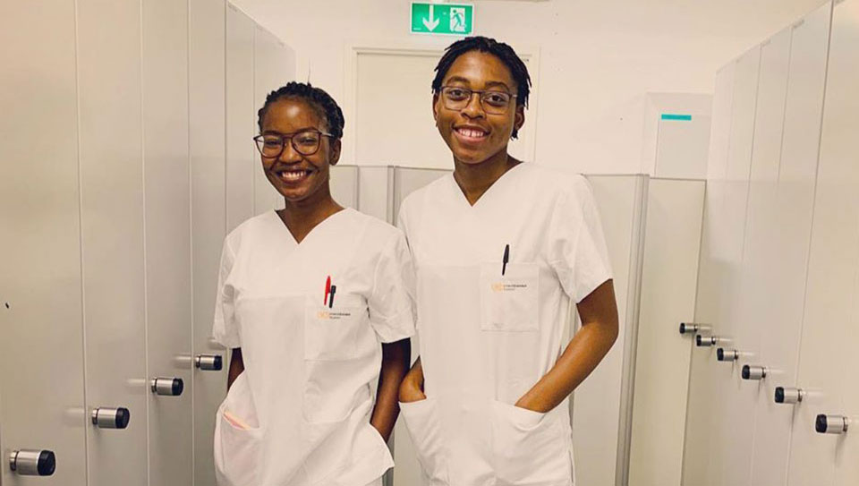 zwei junge Frauen als Krankenpflegerin in weißer Arbeitskleidung