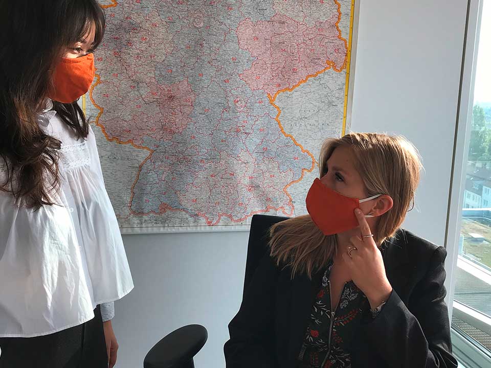 two colleagues in the office wear a mouth-and-nose mask